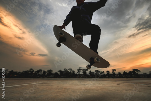 Asian Kids Jumping Tricks - ollie while Skateboarding on-street parking during sunset time., Backlight dark Skateboarder silhouettes photo