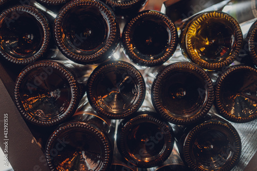 Close-up shot, old bottles of wine in a cellar. Glass wine cabinets covered with dust due to long storage. Warm, muted tones. Bottles textere. photo