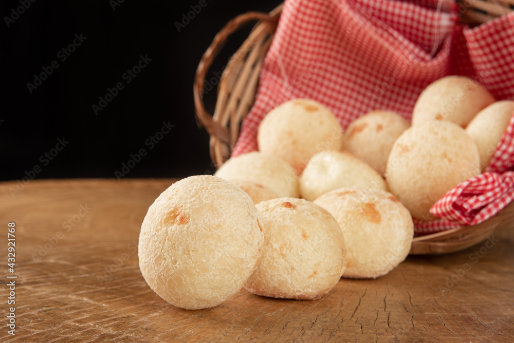 Brazilian cheese bread, basket with checkered cloth with cheese breads on rustic wood, selective focus. Brazilian cheese bread, basket with checkered cloth with cheese breads on rustic wood, selective focus.