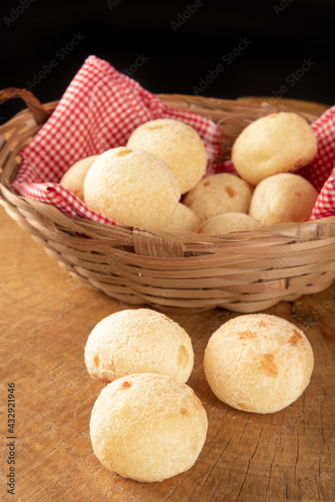 Brazilian cheese bread, basket with checkered cloth with cheese breads on rustic wood, selective focus. Brazilian cheese bread, basket with checkered cloth with cheese breads on rustic wood, selective focus.