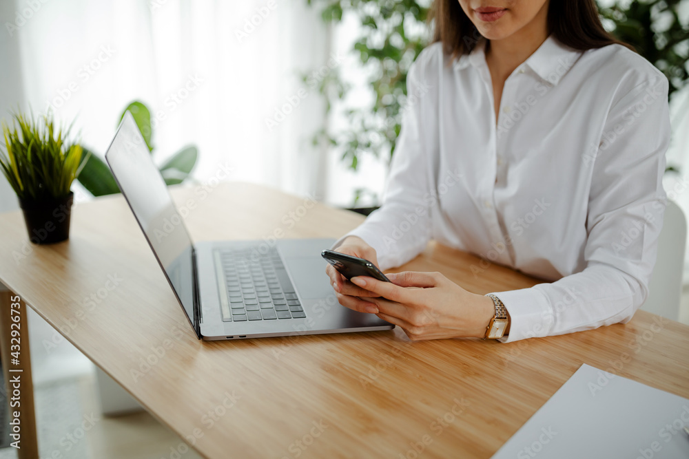 Businesswoman using mobile phone and writing a message while sitting on the table in office. Businesswoman using mobile phone and writing a message while sitting on the table in office.