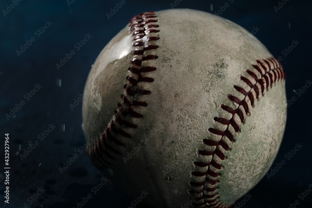 Dark wet baseball covered in water for game rain delay concept, close up color view of old used ball on background. Dark wet baseball covered in water for game rain delay concept, close up color view of old used ball on background.