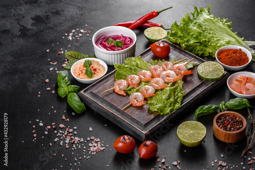 Tasty freshly prepared shrimp with spices and herbs on a wooden board on a dark concrete background