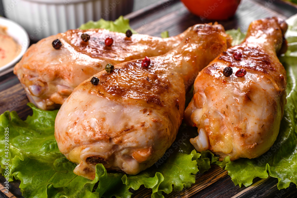Tasty grilled chicken legs with spices and herbs on a wooden board on a dark concrete background Tasty grilled chicken legs with spices and herbs on a wooden board on a dark concrete background