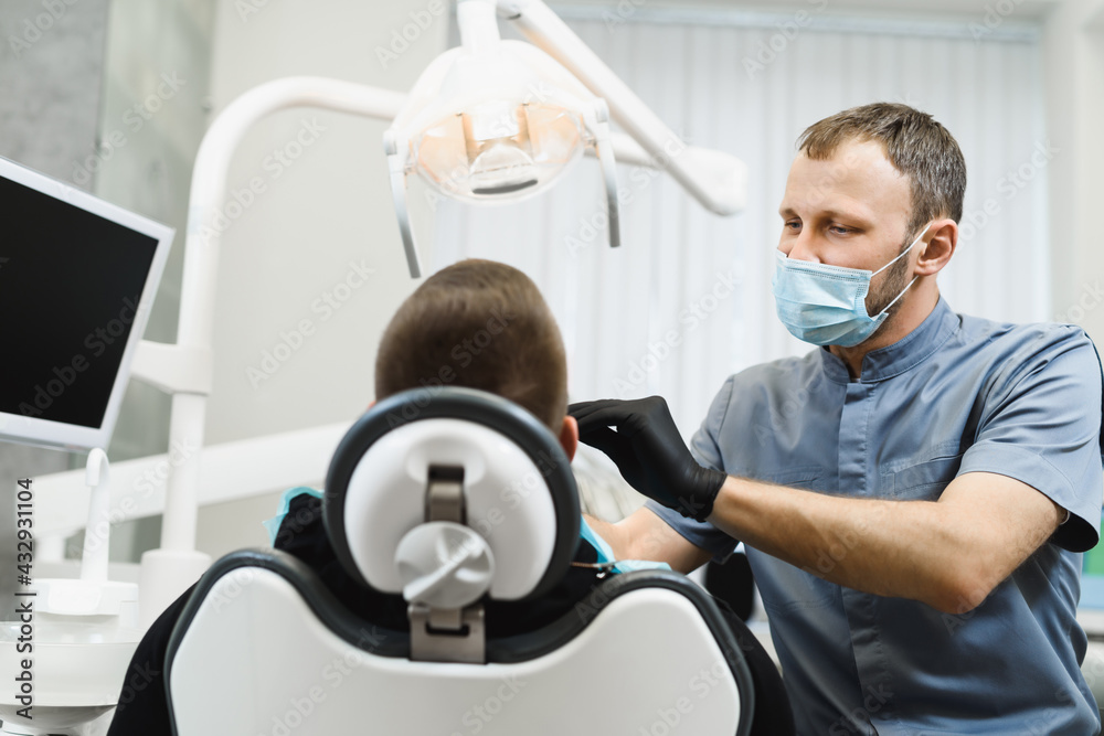 Male dentist examines the patient before treatment. Consultation in dentistry. Checking the health of your teeth. A man with braces came for a checkup