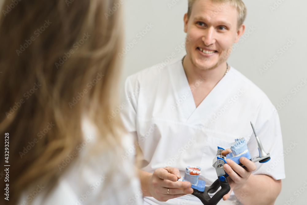 Male dentist doctor talking with woman patient and showing a dental model in modern dentistry Male dentist doctor talking with woman patient and showing a dental model in modern dentistry