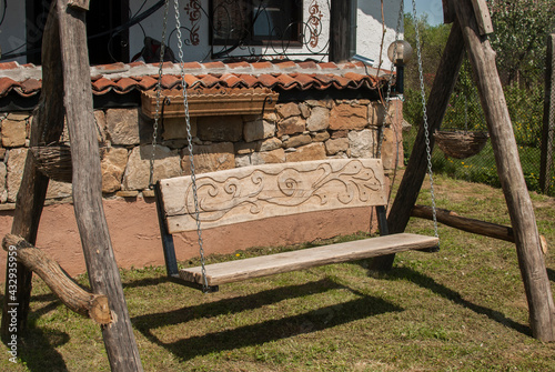 Old rural wooden swing bench in village house garden
