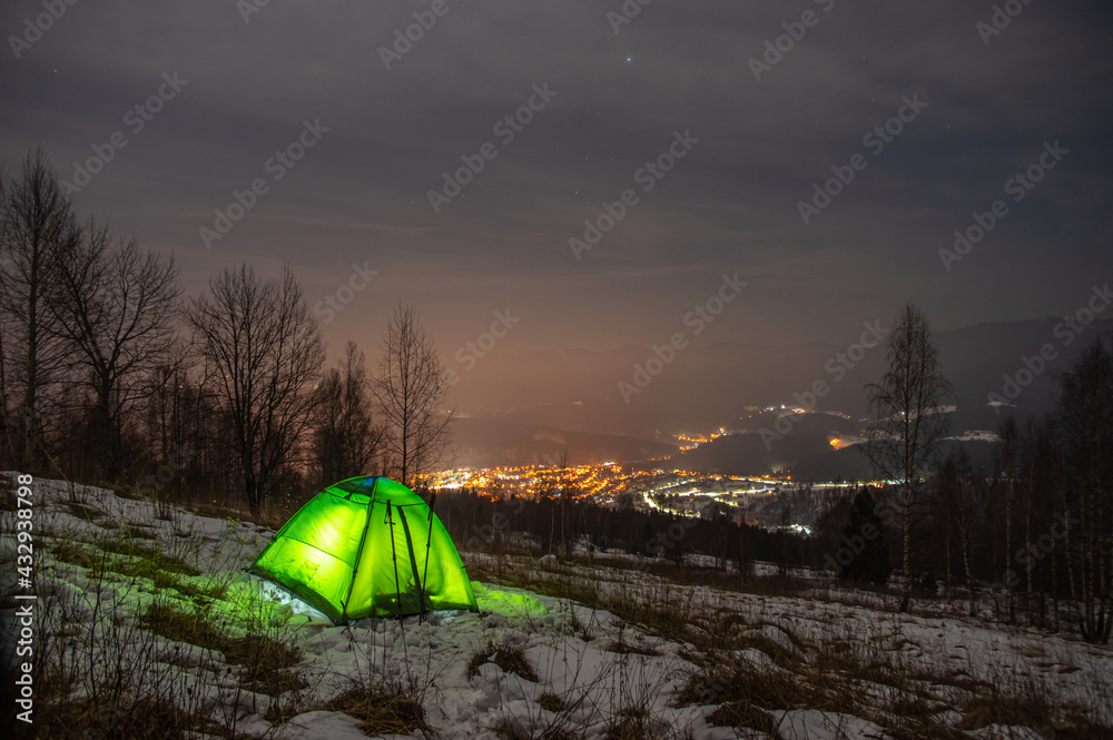 Yellow tent in winter forest at night