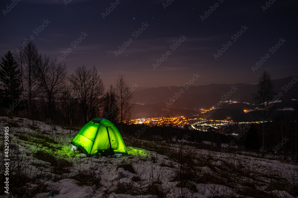 Yellow tent in winter forest at night