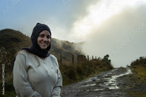 mujer joven con ropa de invierno parada en una montaña sonriendo