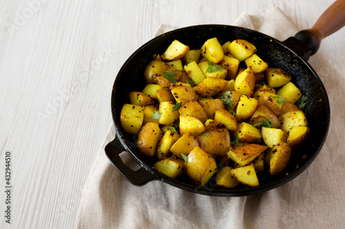 Homemade Roasted Potatoes with Mustard Seeds in a cast-iron pan, side view. Space for text.