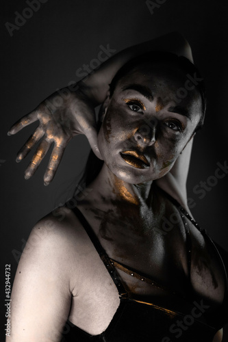 brunette with skin covered with paint in a photo studio on a gray background