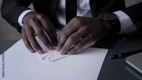 african-American business man makes paper airplane