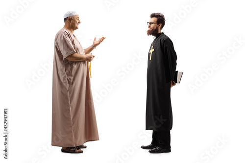 Full length profile shot of a muslim man in traditional clothes talking to a christian priest