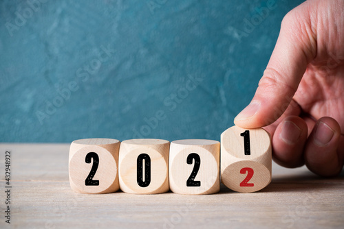 hand turning a cube from 2021 to 2022 on wooden background photo