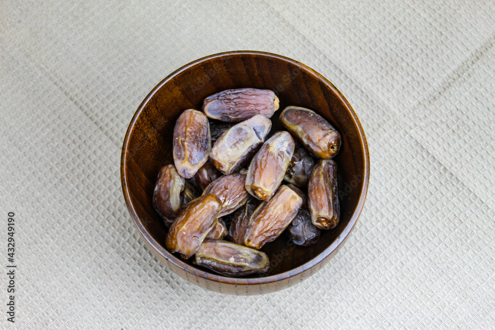 Wooden bowl with dates on the table. Fruit on a wooden tray. Fruit dates. Walnut kernels. The concept of Ramadan. Wooden bowl with dates on the table. Fruit on a wooden tray. Fruit dates. Walnut kernels. The concept of Ramadan.