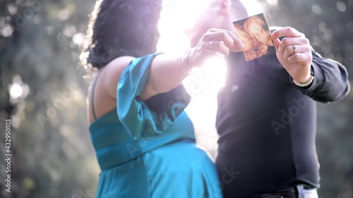 happy couple of future parents shows the ultrasound of the unborn child
