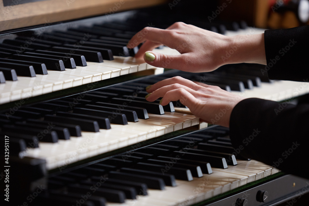Fototapeta premium Close- up of a woman's hands playing a three-manual electronic organ. Musical education concept.