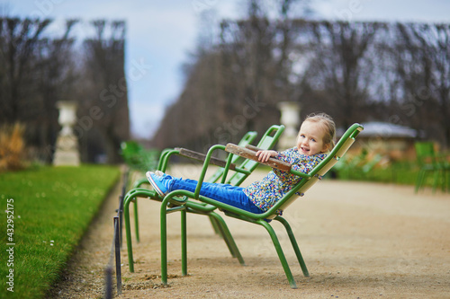 Happy cheerful toddler girl sitting on green chair in Tuileries Garden of Paris © Ekaterina Pokrovsky