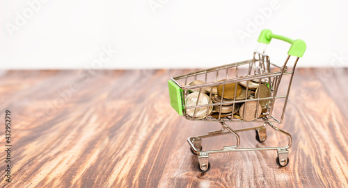 grocery cart with coins on wooden table