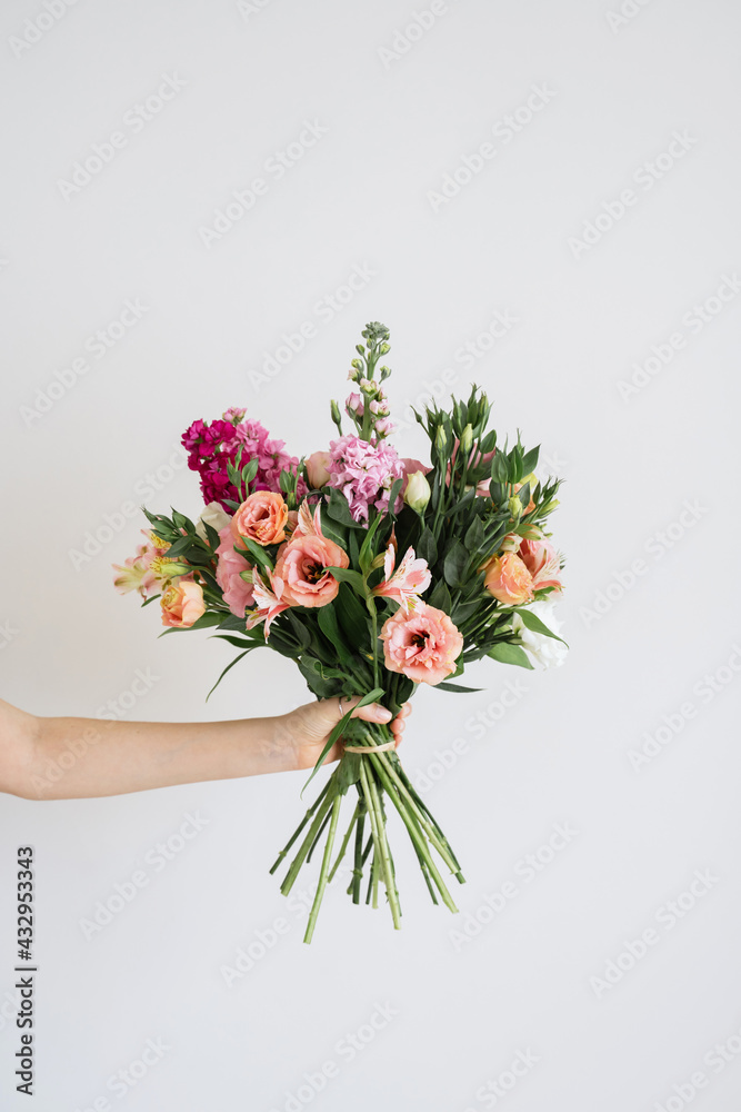 Naklejka premium Cropped shot of female holding big beautiful gorgeous spring wedding bouquet of different fresh flowers in full bloom against white background with copy space for text. Floristry work concept