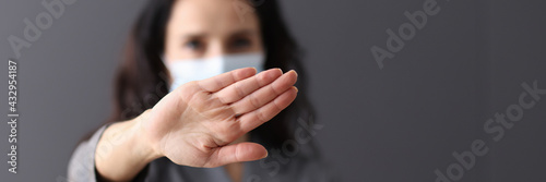 Fotografie Woman in medical protective mask holds her hands in negative gesture