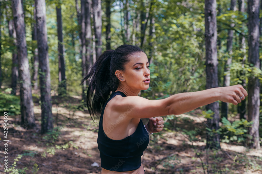 Close up portrait of a sexy brunette exercising kickbox with direct punches in the middle of the forest Close up portrait of a sexy brunette exercising kickbox with direct punches in the middle of the forest