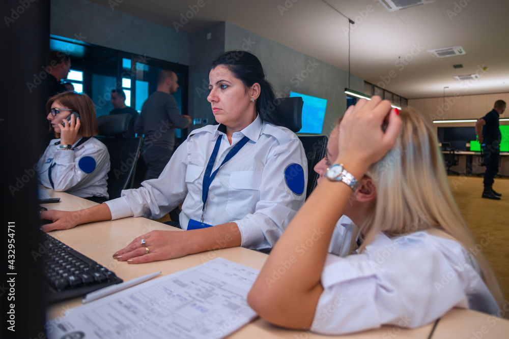 Fototapeta premium Female security guards working on computers while sitting in the main control room