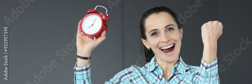 Happy woman holding red alarm clock closeup photo