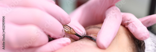 Master performs permanent makeup on eyelids by making decorative arrow