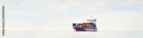 Large cargo container ship sailing in an open Baltic sea on a clear day. Freight transportation, nautical vessel, logistics, economy, industry, global communications