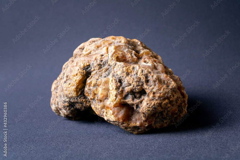 Stone in shades of red, white and with several holes and irregularities on a dark black background with a light from left to right. Stone in shades of red, white and with several holes and irregularities on a dark black background with a light from left to right.