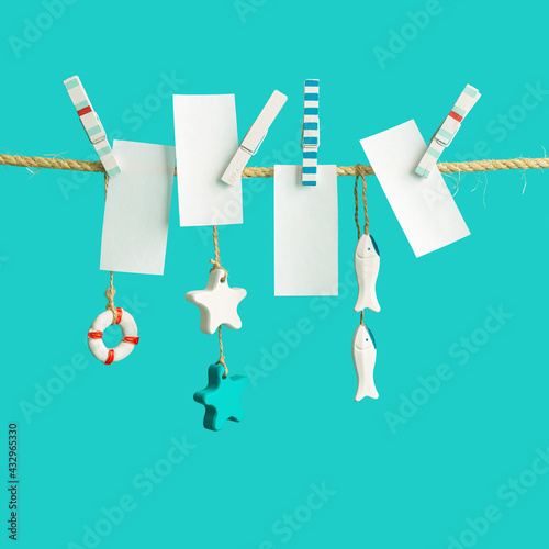 White pieces of paper  sea lifestyle decorations hanging on clothespins on rope, empty space for letters or text. Summer concept