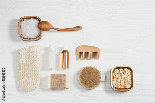 Flat lay composition with bath accessories with small bottles with gel and shampoo, soap, sea salt, washcloth on table with copy space.