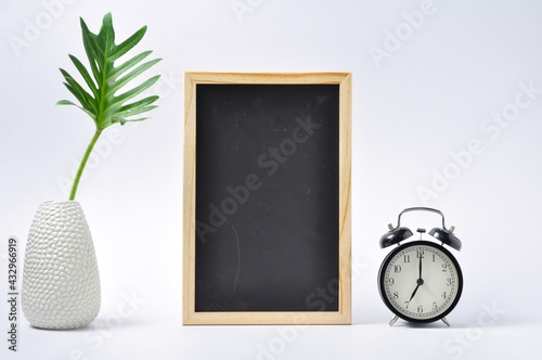 white vase with ablackboard and ablack clock on white background. minimal style photo