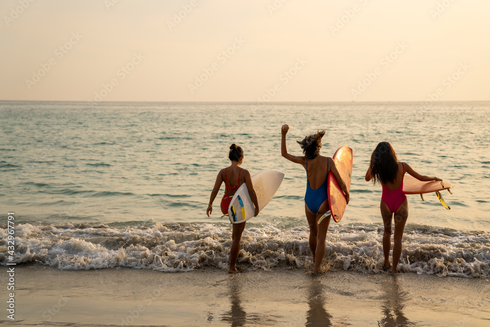 Confidence Asian woman girl friends in swimwear holding surfboard and walking together on the beach at summer sunset. Female friendship enjoy outdoor activity lifestyle play extreme sports surfing Confidence Asian woman girl friends in swimwear holding surfboard and walking together on the beach at summer sunset. Female friendship enjoy outdoor activity lifestyle play extreme sports surfing