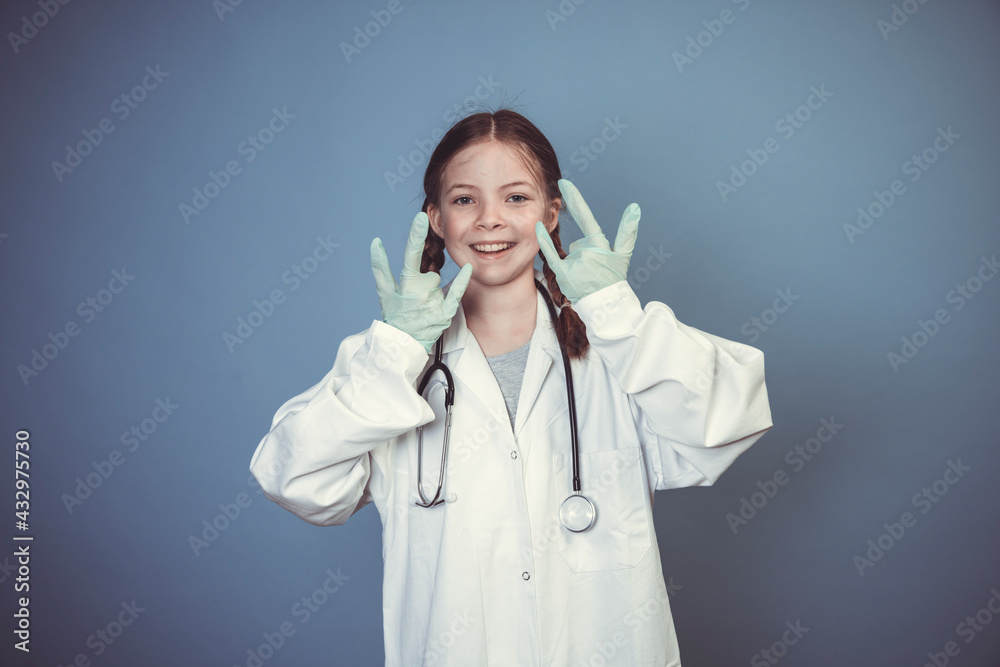 beautiful young girl dressed as doctor with green rubber gloves and stethoscope in front of blue background beautiful young girl dressed as doctor with green rubber gloves and stethoscope in front of blue background