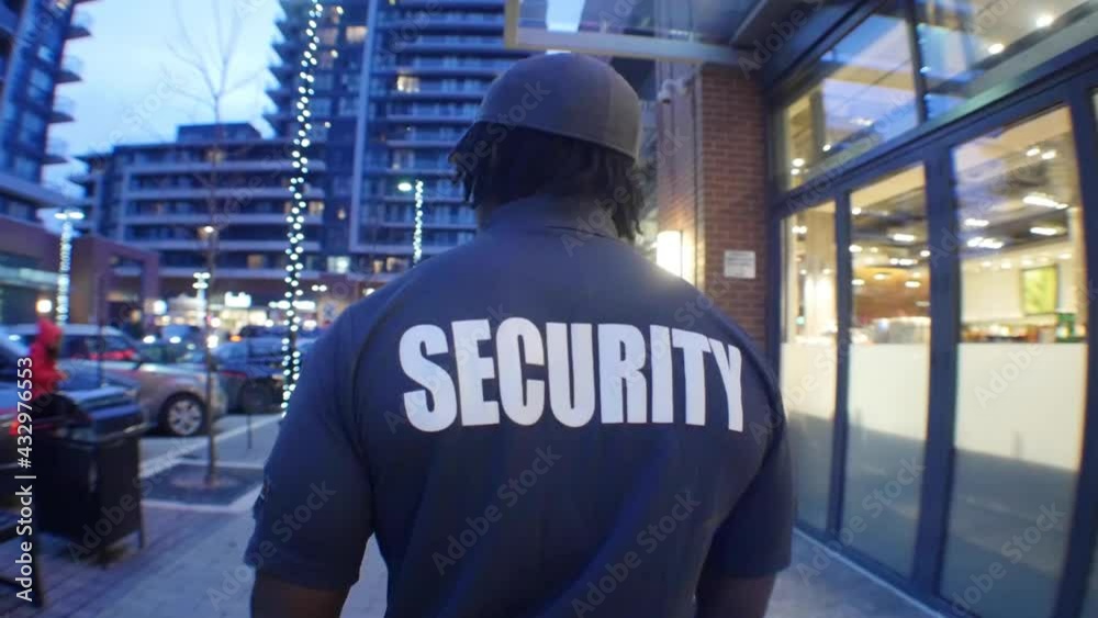 Tracking shot of security guard in uniform patrolling the commercial area.