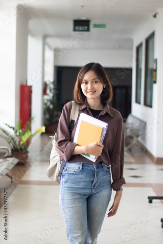 Beautiful young woman with backpack and books outdoors.