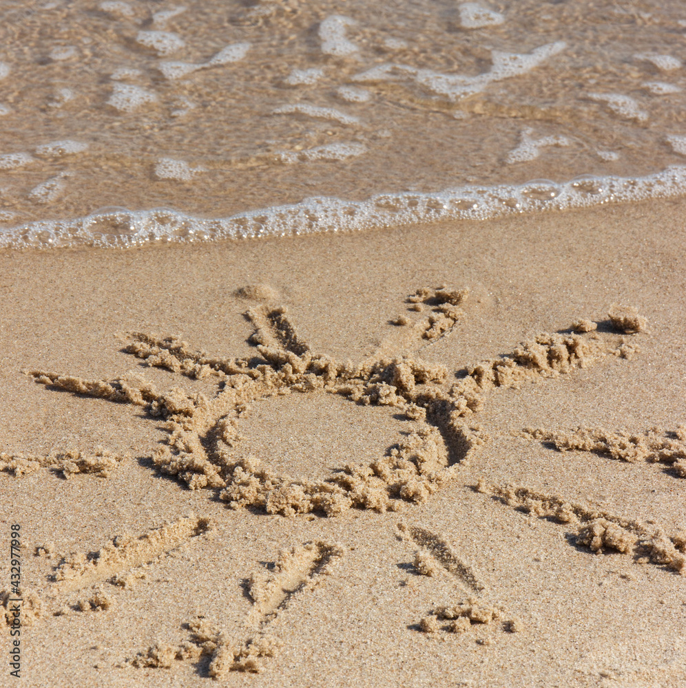 Fototapeta premium Shape of sun with incoming sea wave on sand at beach. Summer and vacation time