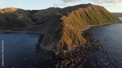 Flying up and away from a cape during a golden sunset. Makara Beach, New Zealand. photo