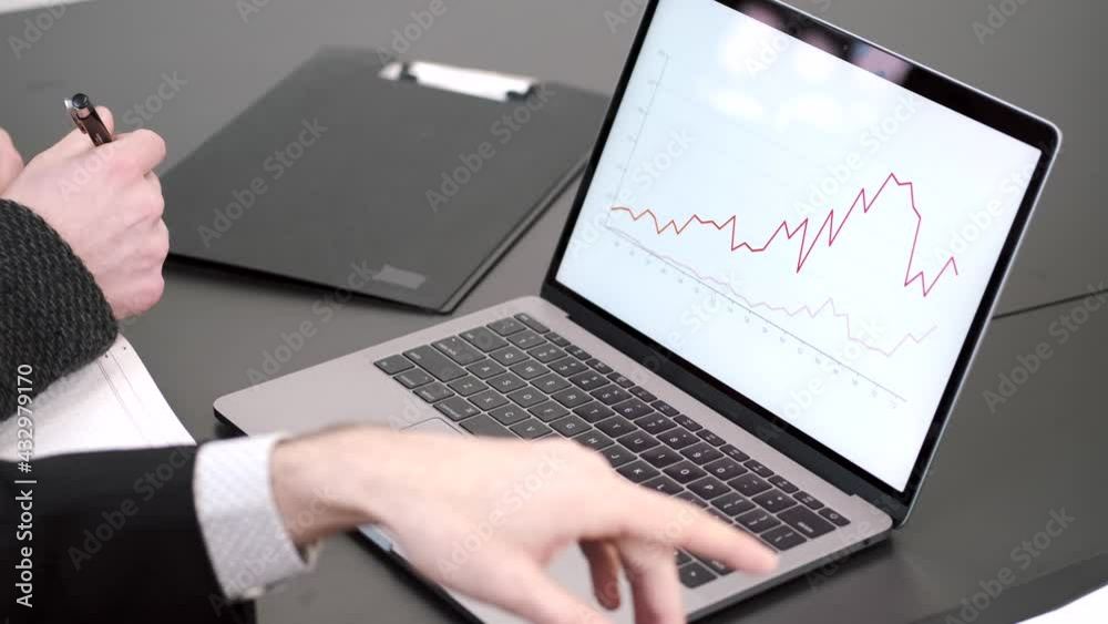 Men's fingers pointing at laptop screen on desk Men's fingers pointing at laptop screen on desk