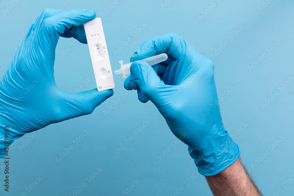 Doctor in blue gloves using a lateral flow covid-19 testing kit Doctor in blue gloves using a lateral flow covid-19 testing kit