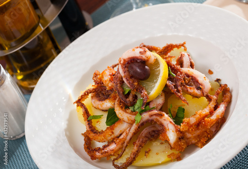Deep fried crispy squid tentacles served with boiled potatoes, fresh lemon and greens..