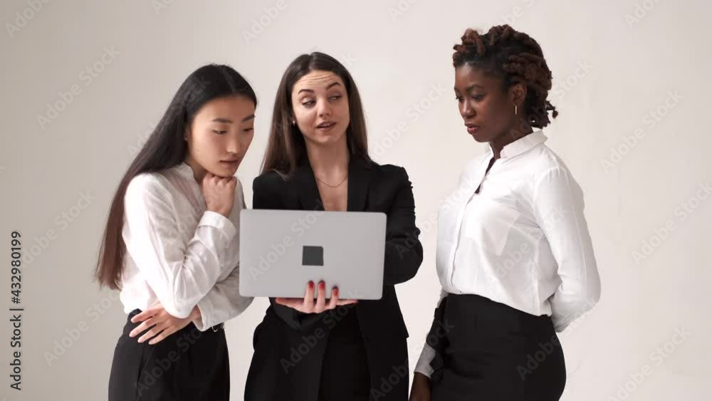 Diverse female coworkers standing with laptop on white background Diverse female coworkers standing with laptop on white background