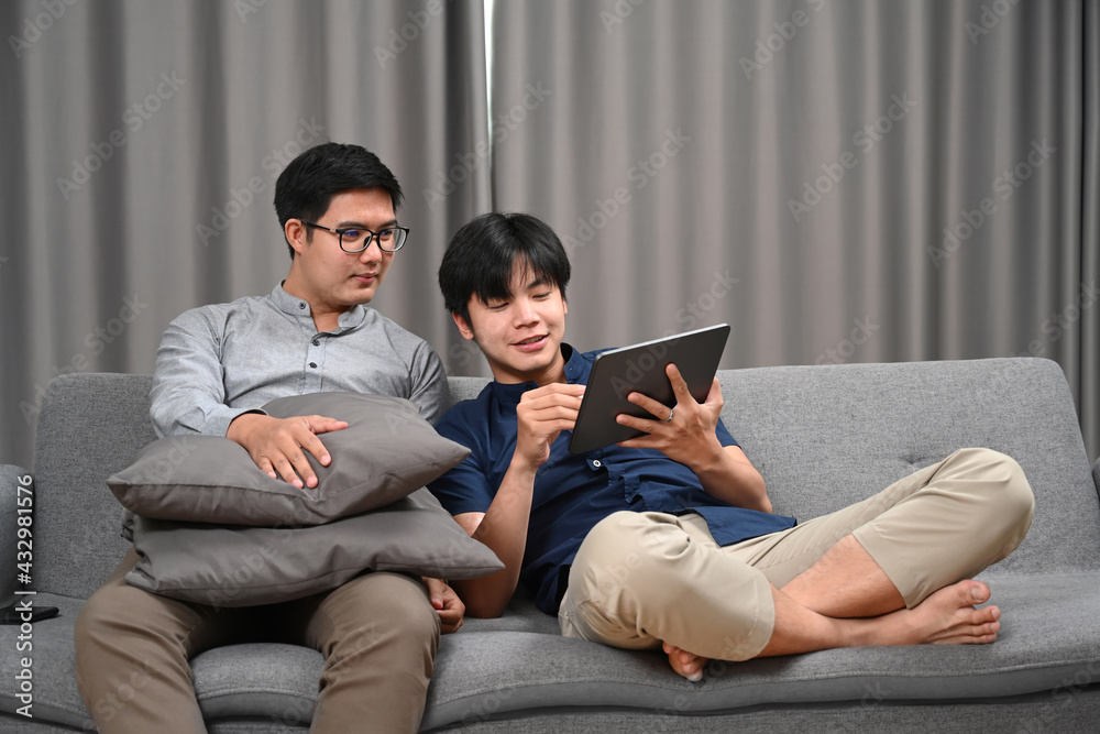 Happy gay couple using digital tablet while spending time together at home. Homosexual, LGBT concept. Happy gay couple using digital tablet while spending time together at home. Homosexual, LGBT concept.