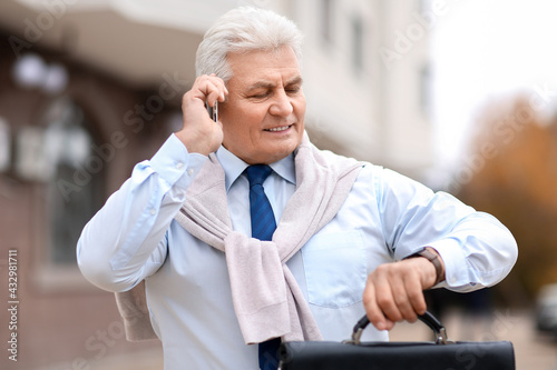 Senior businessman talking by mobile phone outdoors