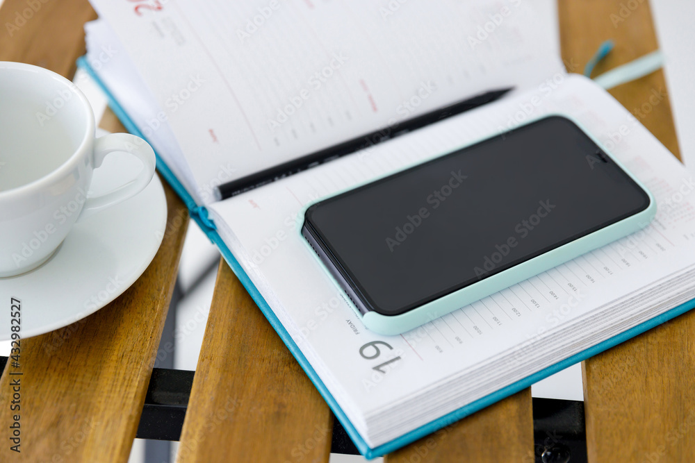 smartphone and notebook for planning affairs lie on wooden table smartphone and notebook for planning affairs lie on wooden table