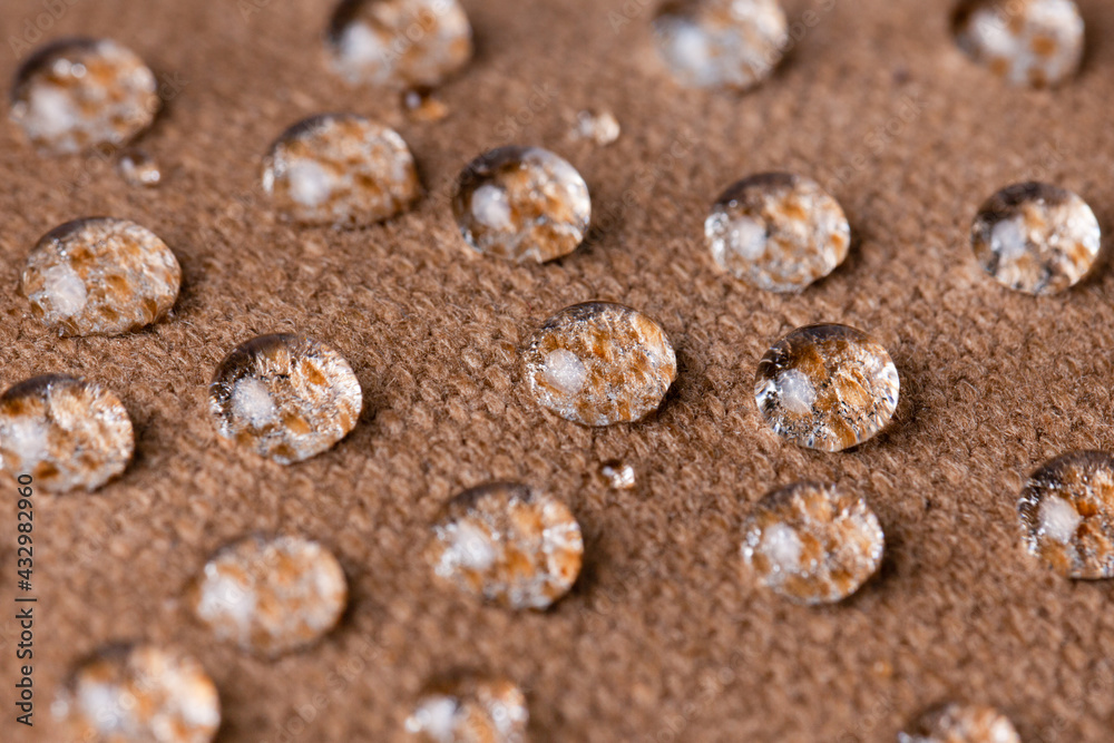 Water drops on waterproof biege or brown fabric close-up. Water resistant textile. 