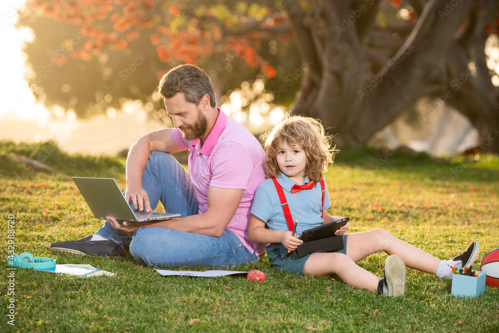 E-Learning family concept. Father and son with tablet computer outside in the park. E-Learning family concept. Father and son with tablet computer outside in the park.